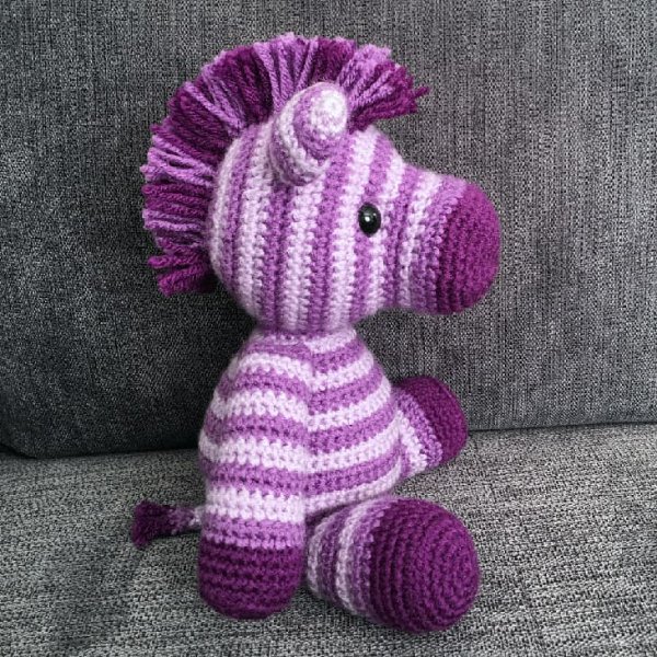 A crochet zebra in shades of purple.