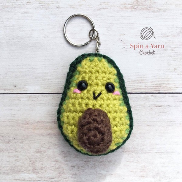 An amigurumi avocado keychain with a cute little face.