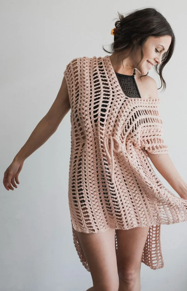 A closeup image of a woman weraing a lacy crochet swim cover.