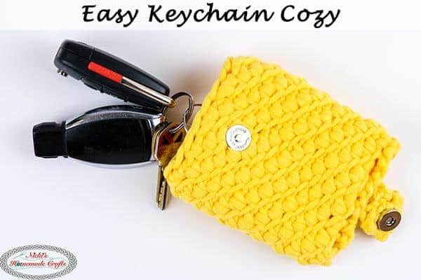 A yellow crochet cozy holding keys.