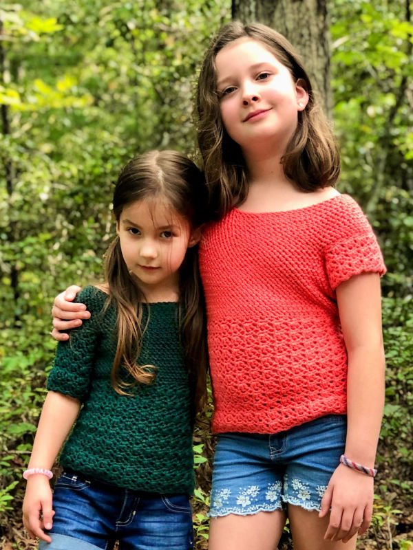 Two children wearing matching crochet t-shirts.