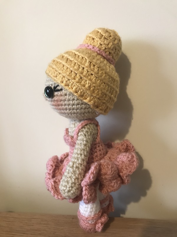 A crochet ballerina doll in a pink tutu with a blonde bun.