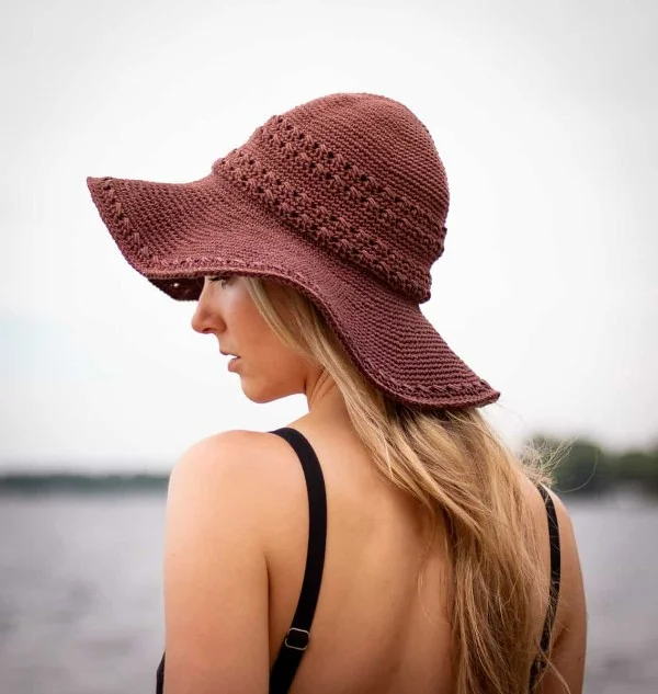 Back view of a woman at the beach wearing a rust coloured crochet sun hat.