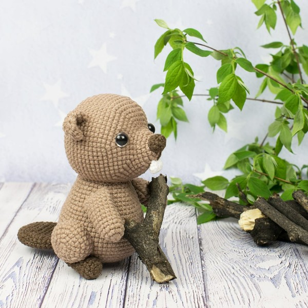 A crochet beaver with woode and greenery.