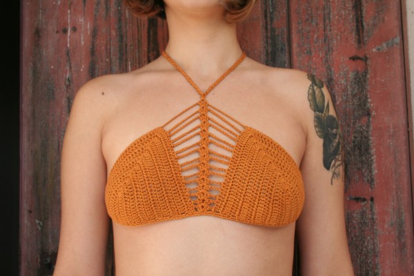 A woman wearing an oragne crochet crop top.
