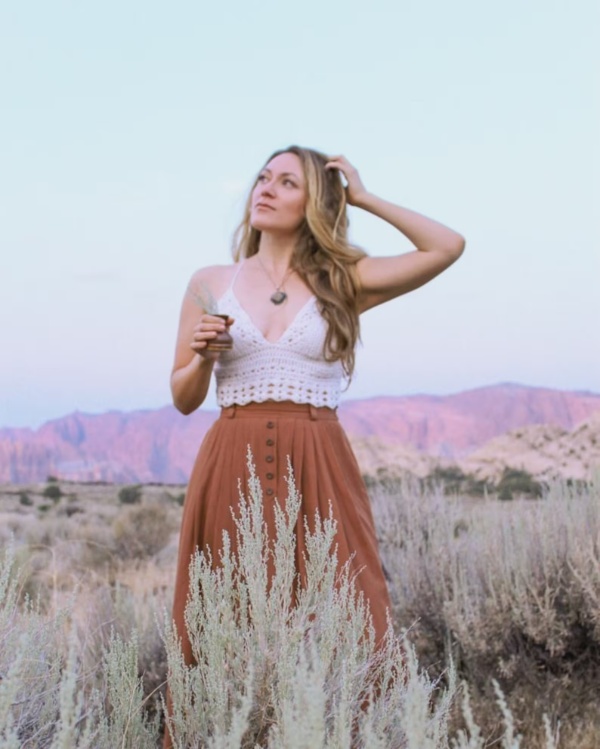 A woman outdoors wearing a long skirt and a white crochet bralette.