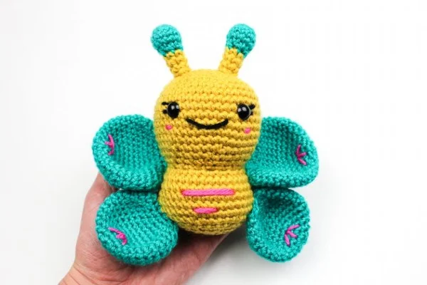 A jade green and yellow crochet butterfly amigurumi.