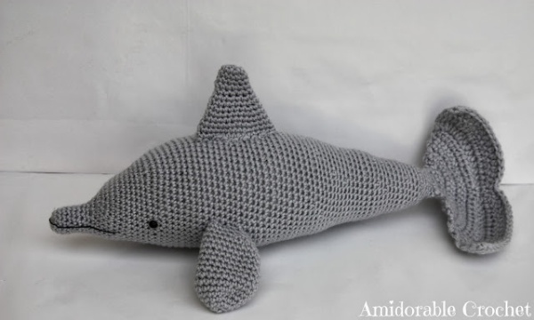 A grey crochet dolphin amigurumi.