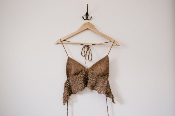 A crochet bralette on a clothes hanger.