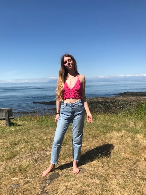 A woman outdoors wearing jeans and a pink crochet bralette.