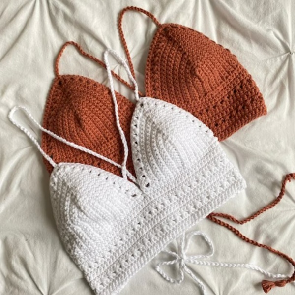 A flatlayimage of two crochet bralettes, one rust coloured and one white.