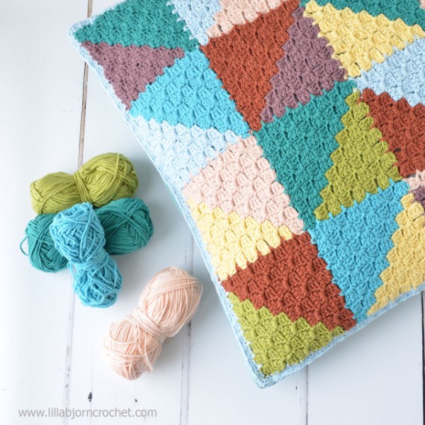 Multi-coloured c2c crochet pillow with trianglew motif.