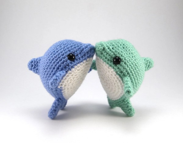 Two chubby crochet dolphin toys.