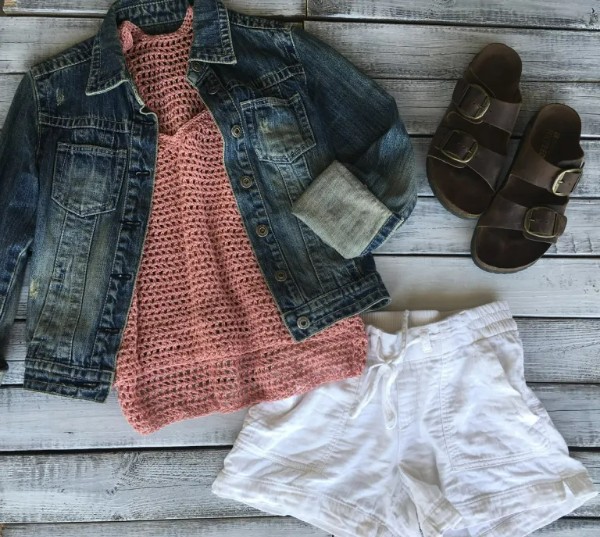 A flat lay image of a crochet racerback tank top with a jacket and shorts.