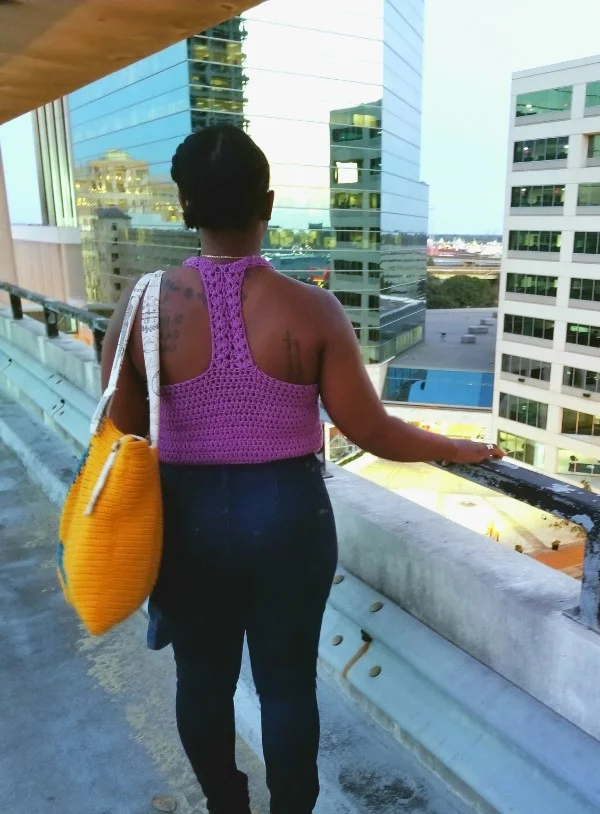 Back view of a woman wearing a bright coloured racerback crochet tank top.