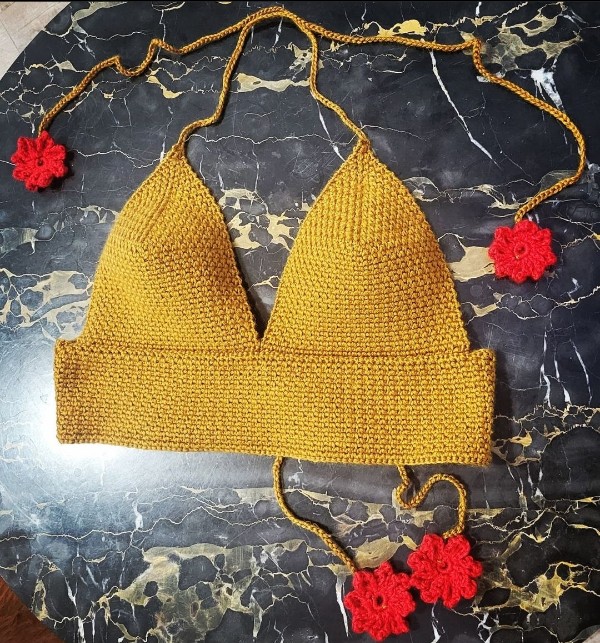 A yellow crochet braleete with flower ties.
