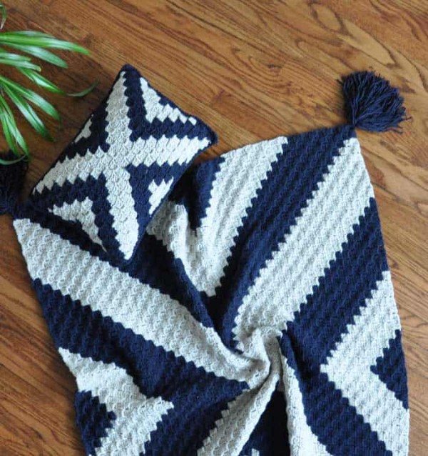 A navy and white geormetric crochet pillow and matching throw.