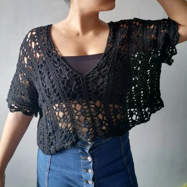 A woman wearing a charcoal grey, cropped crochet lace top.