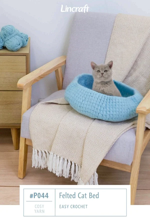 A cat in a blue crochet cat bed in a chair.