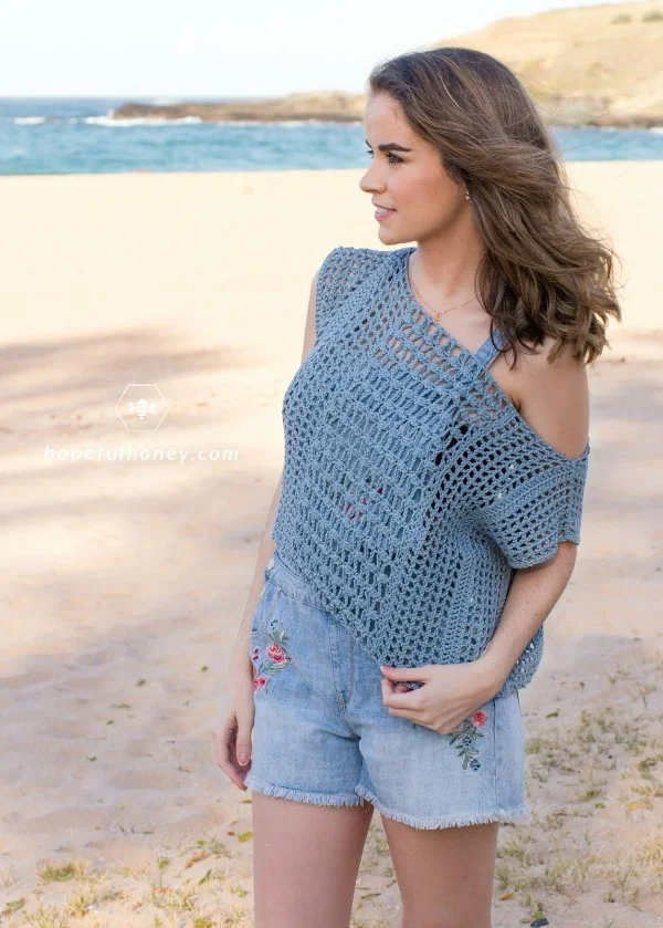 A woman wearing a blue, off the shoulder lacy crochet top.