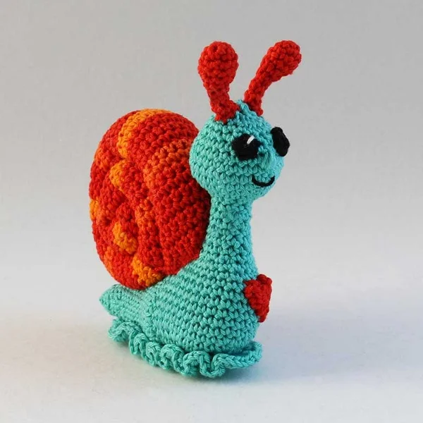 A brightly coloured crochet snail o a white background.