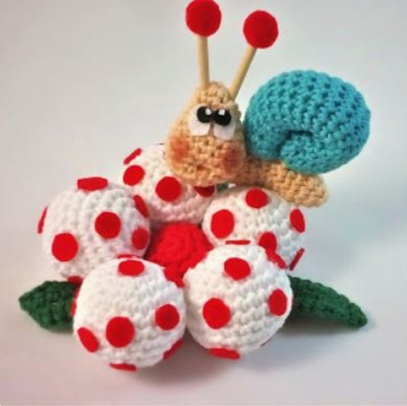 Cartoon-style crocht snail on a spotted red and white flower.