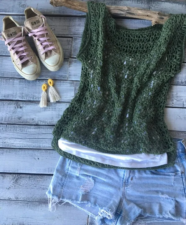 A flat lay picture of a forest green crochet lace top, jeans shorts and sneakers.