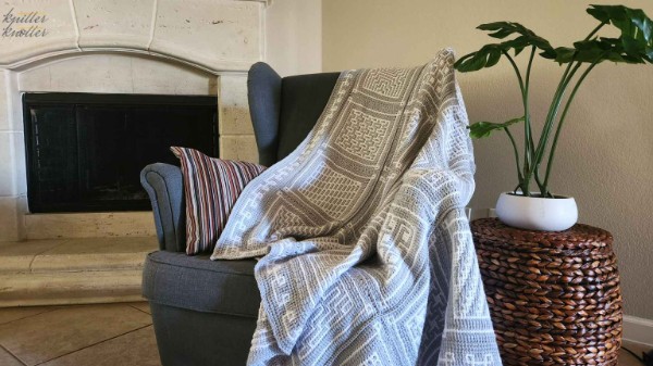 A tunisian crochet blanket draped over alounge chair.