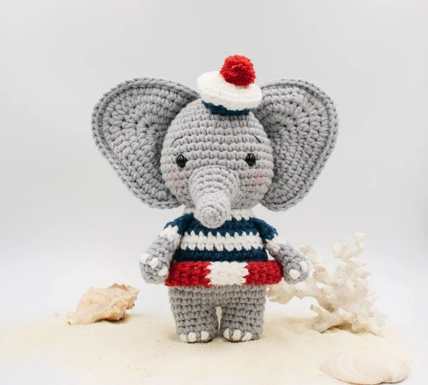 A crochet elephant wearing a sailers outfit.