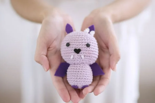 A purple and pink crochet bat with fangs.
