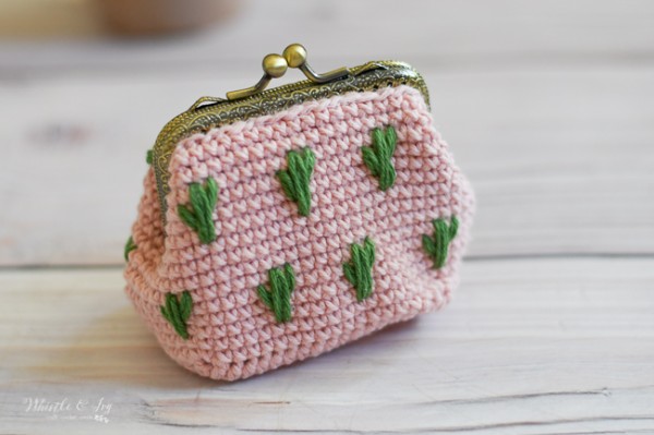 A pink crochet coin purse with emoriderd cactus motifs.