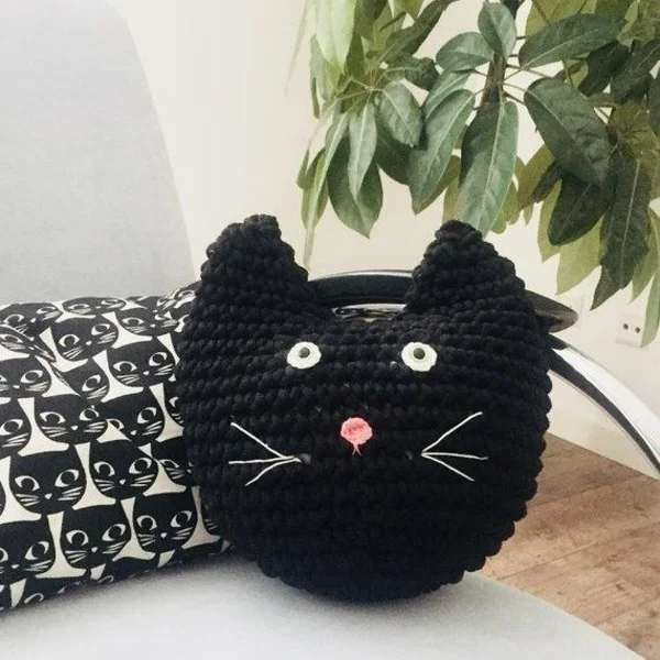 A black cat shaped crochet pillow.