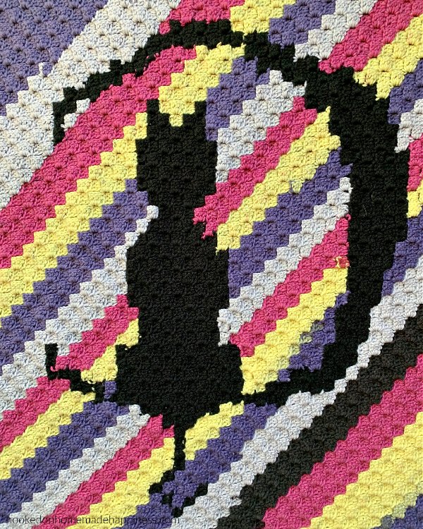 A Halloween crochet blnaket with a black cat silhouette.