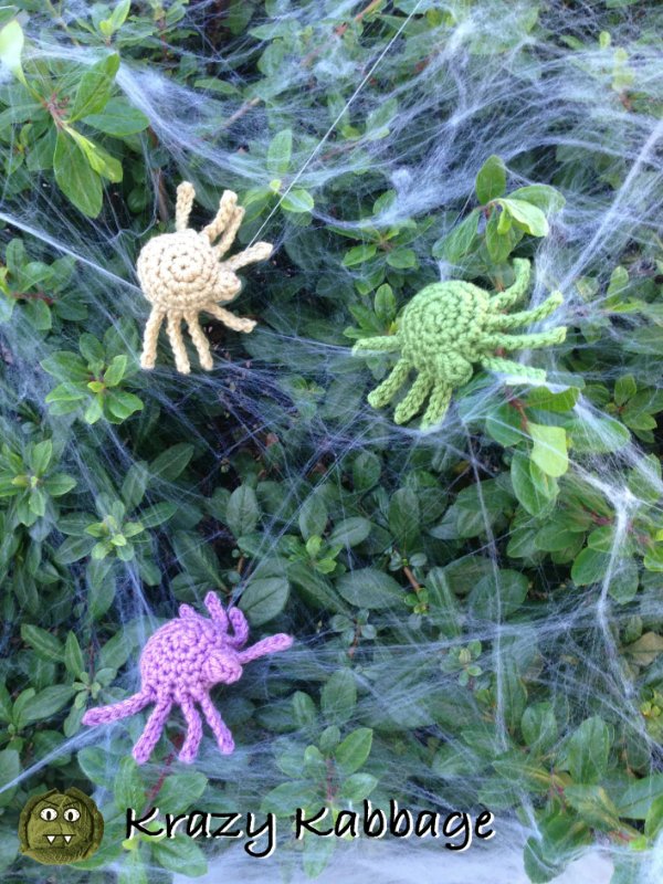 Three brightly coloured crochet spiders and spider webs.