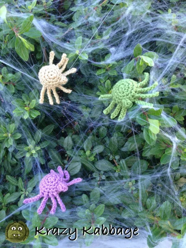 Three brightly coloured crochet spiders and spider webs.
