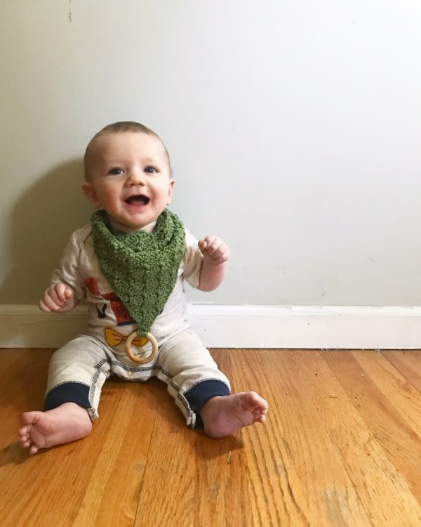 A baby boy wearing a green crochet bandanna bib.