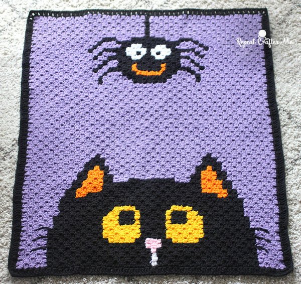 A c2c crochet halloween blanket with a cat and a spider.