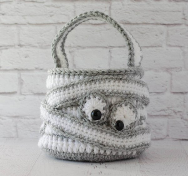 A grey and white crochet mummy bag.