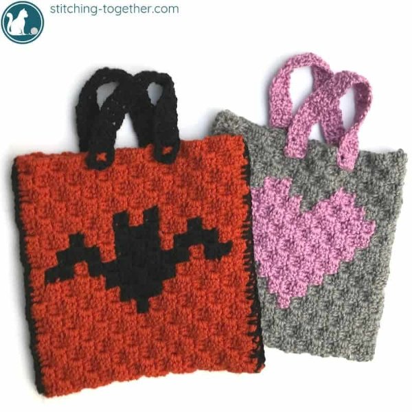 Two crochet Halloween treat bags, one with a bat motif and the other with a love heart.