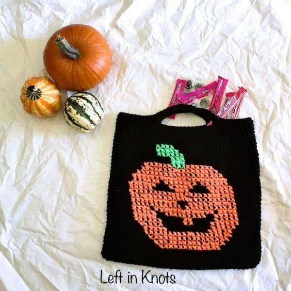 A crochet halloween treat bag with a jack-o-lantern motif.