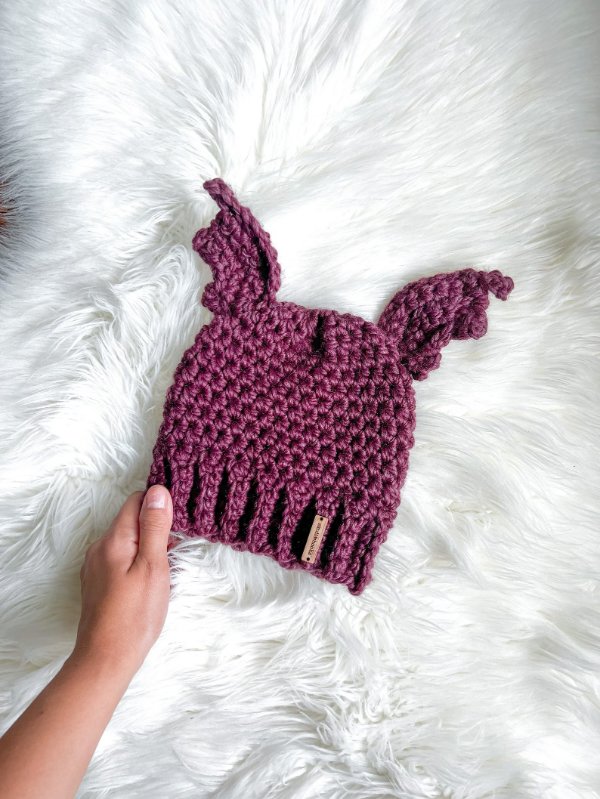 A purple crochet beanie with bat wings.