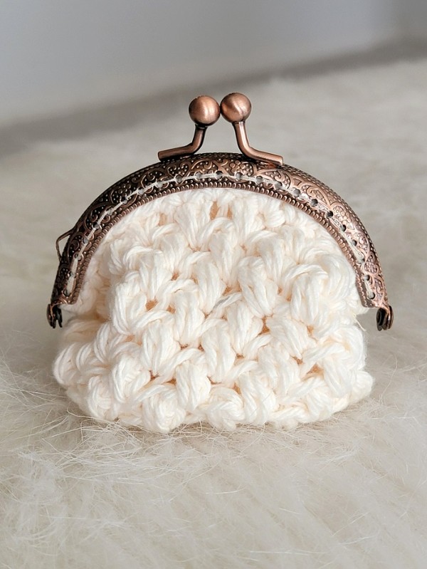 A cream coloured crochet coin purse with puff stitch.