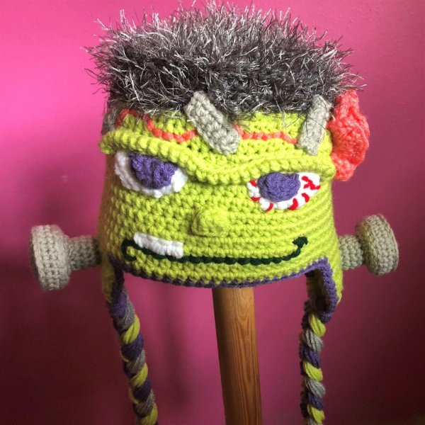 A crochet Frankenstein hat on a stick.
