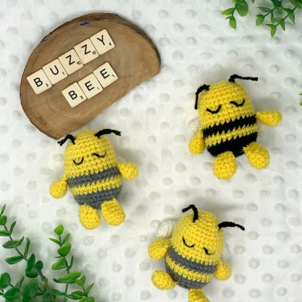 Three small crochet bees on a white background with green leaves.