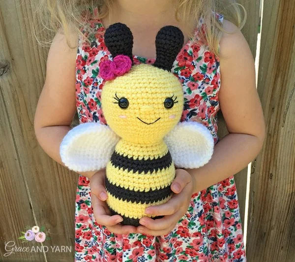 A child with a crochet bee toy.