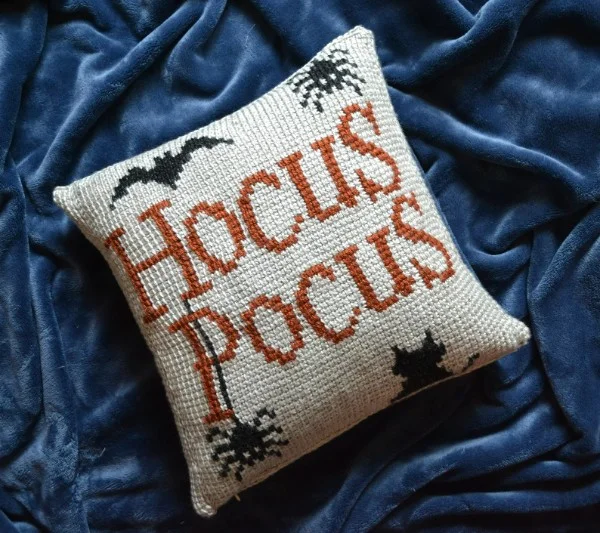 Halloween crochet pillow with bats and spiders on a blue silk background.