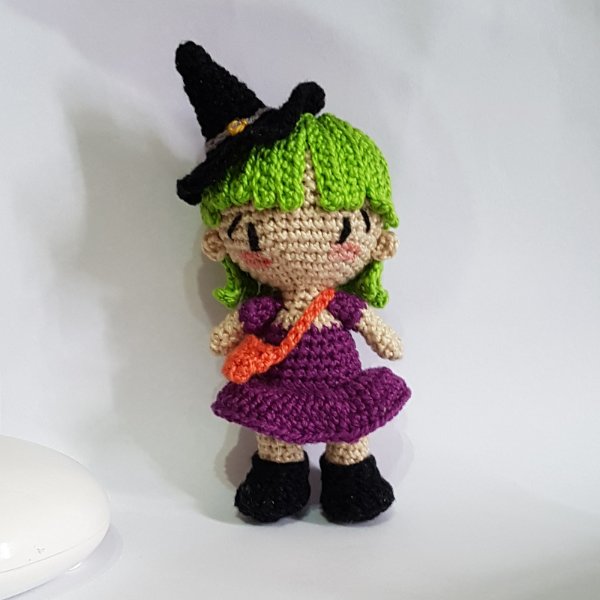 An amigurumi crochet witch doll with green hair.