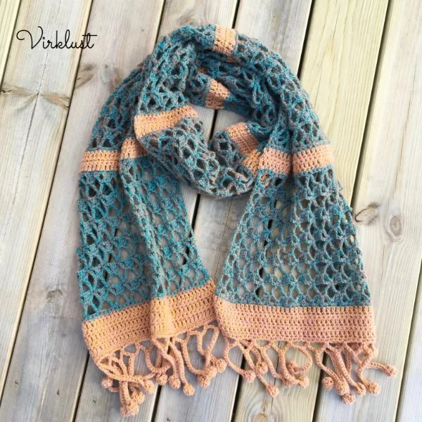 A blue, lacy crochet scarf with stripes and tassels.