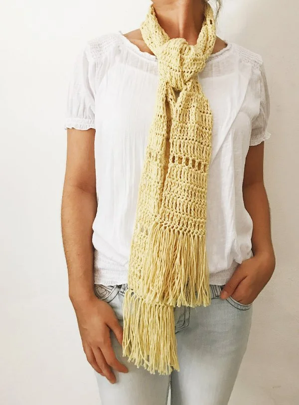 Close-up view of a womand wearing a lacy crochet scarf iwth jeans and a white t-shirt.