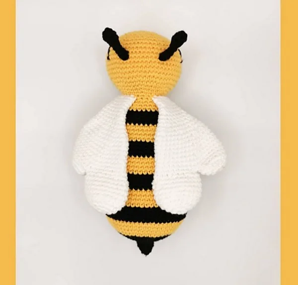 A top down view of a crochet bee with white wings.